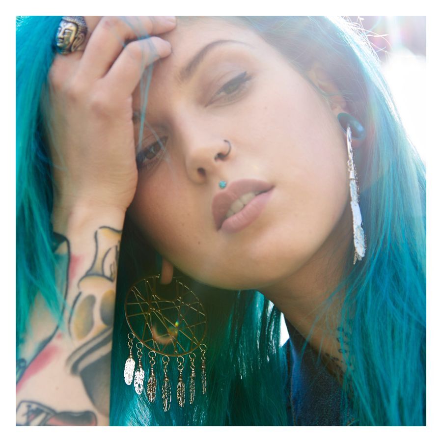 Donna con capelli turchesi indossa grandi orecchini dreamcatcher in argento
