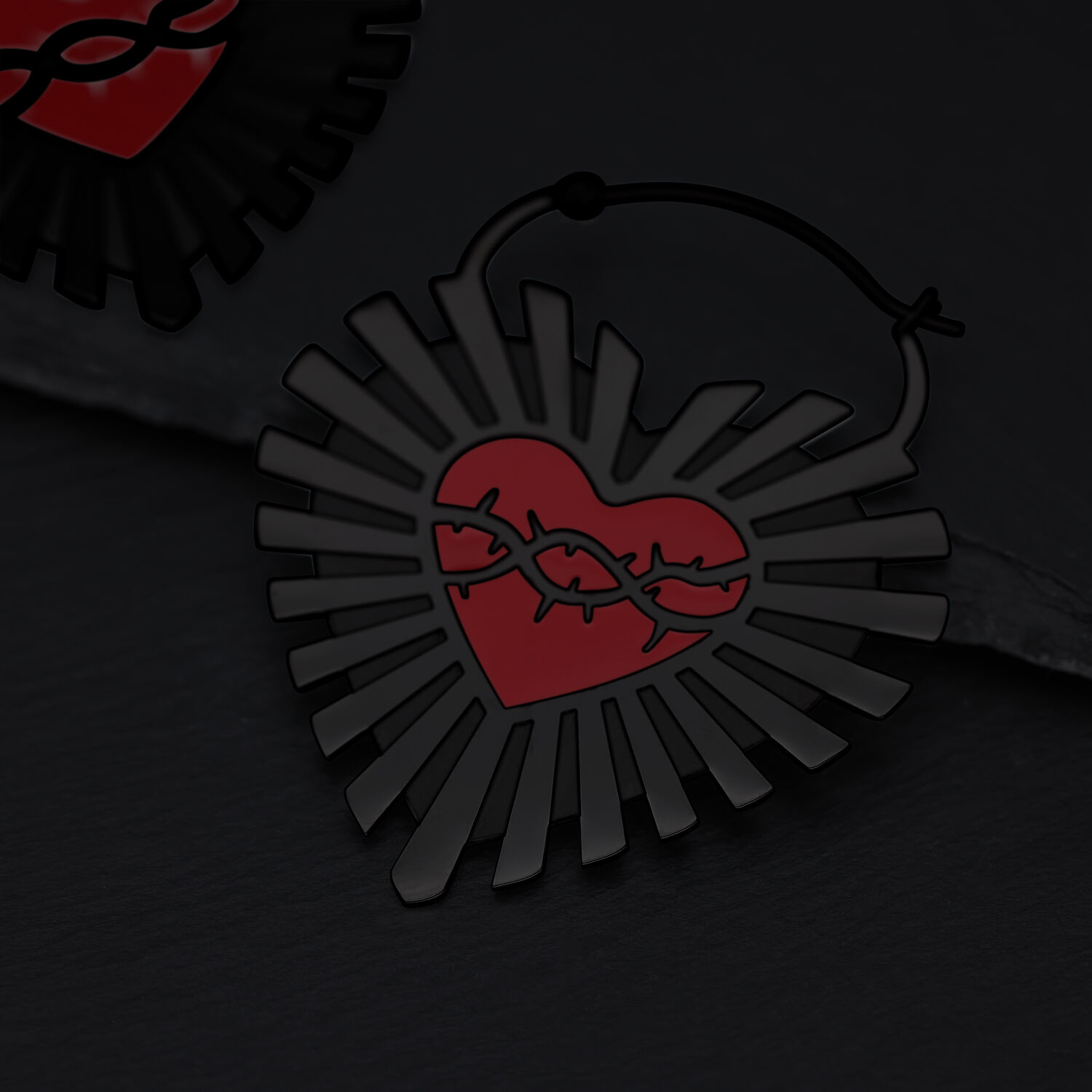 Orecchini neri a forma di cuore con design di filo spinato su sfondo scuro