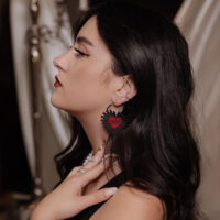 Donna con lunghi capelli scuri indossa orecchini a cerchio Sacred Heart neri in acciaio chirurgico