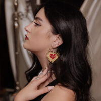 Orecchini a Cuore Dorati con Design a Filo Spinato Orecchini a cuore dorati con filo spinato nell'orecchio di una donna con capelli scuri