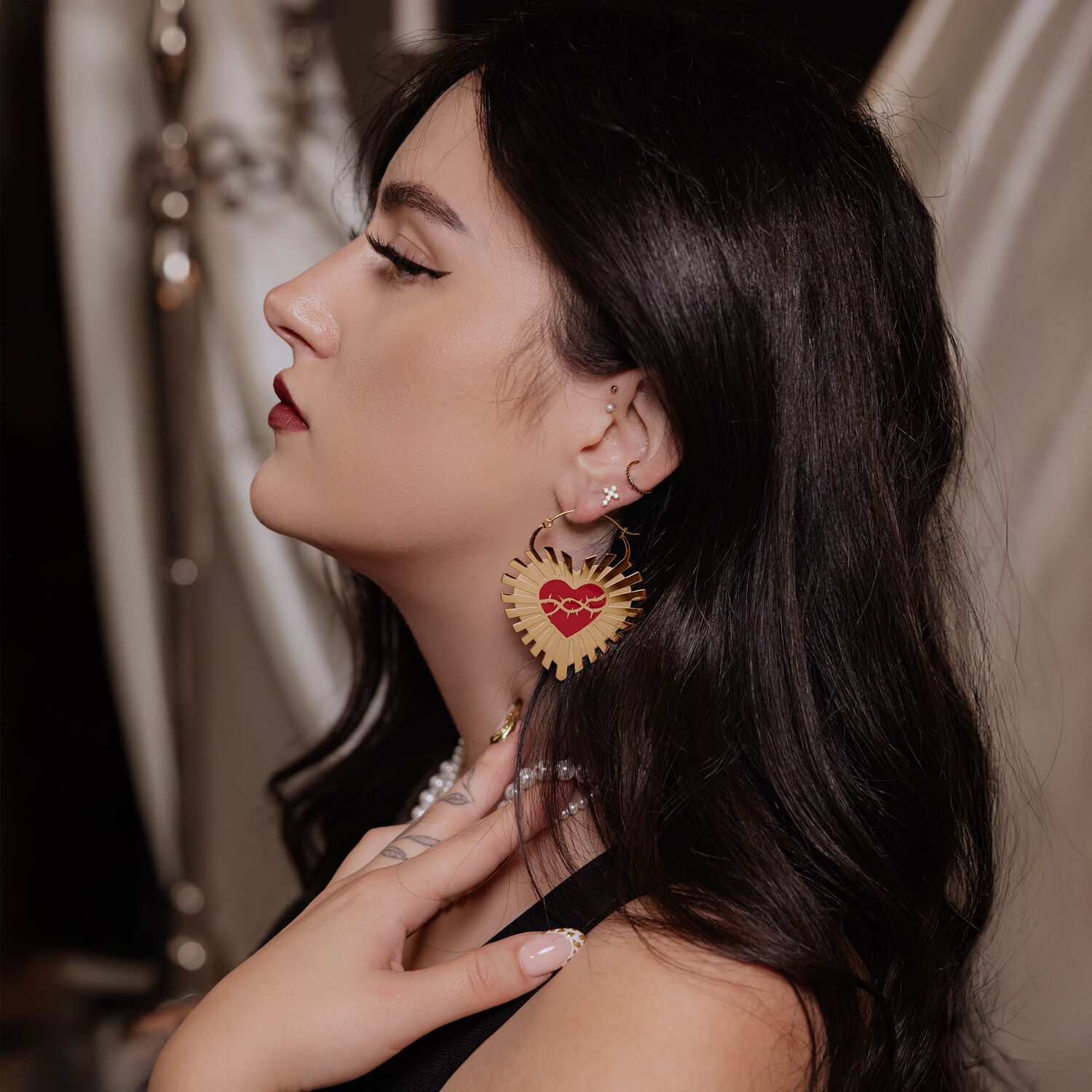 Orecchini a Cuore Dorati con Design a Filo Spinato Orecchini a cuore dorati con filo spinato nell'orecchio di una donna con capelli scuri