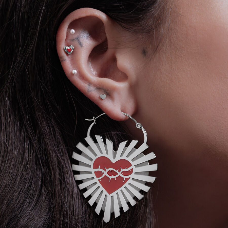 Orecchini in argento a forma di cuore con motivo di filo spinato su un orecchio