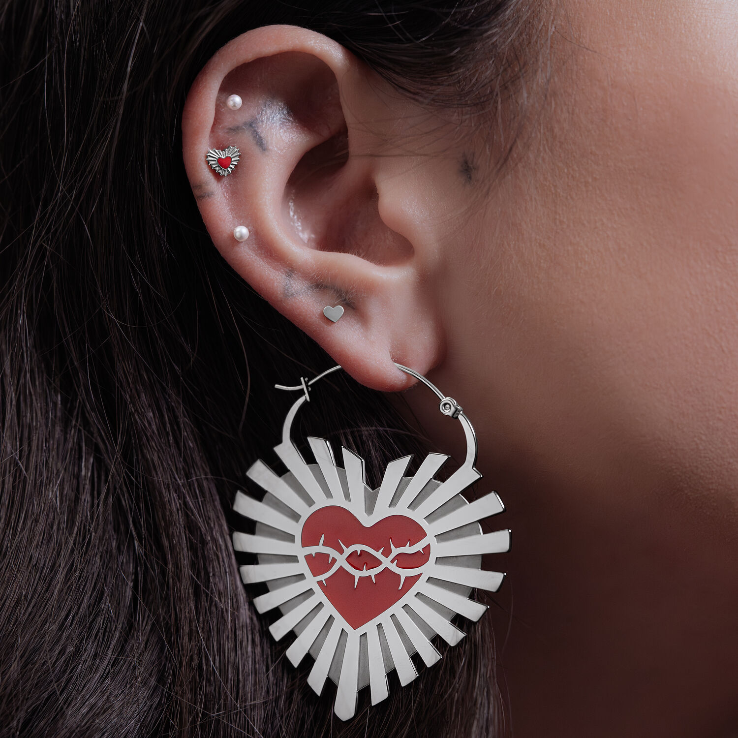 Orecchini in argento a forma di cuore con motivo di filo spinato su un orecchio