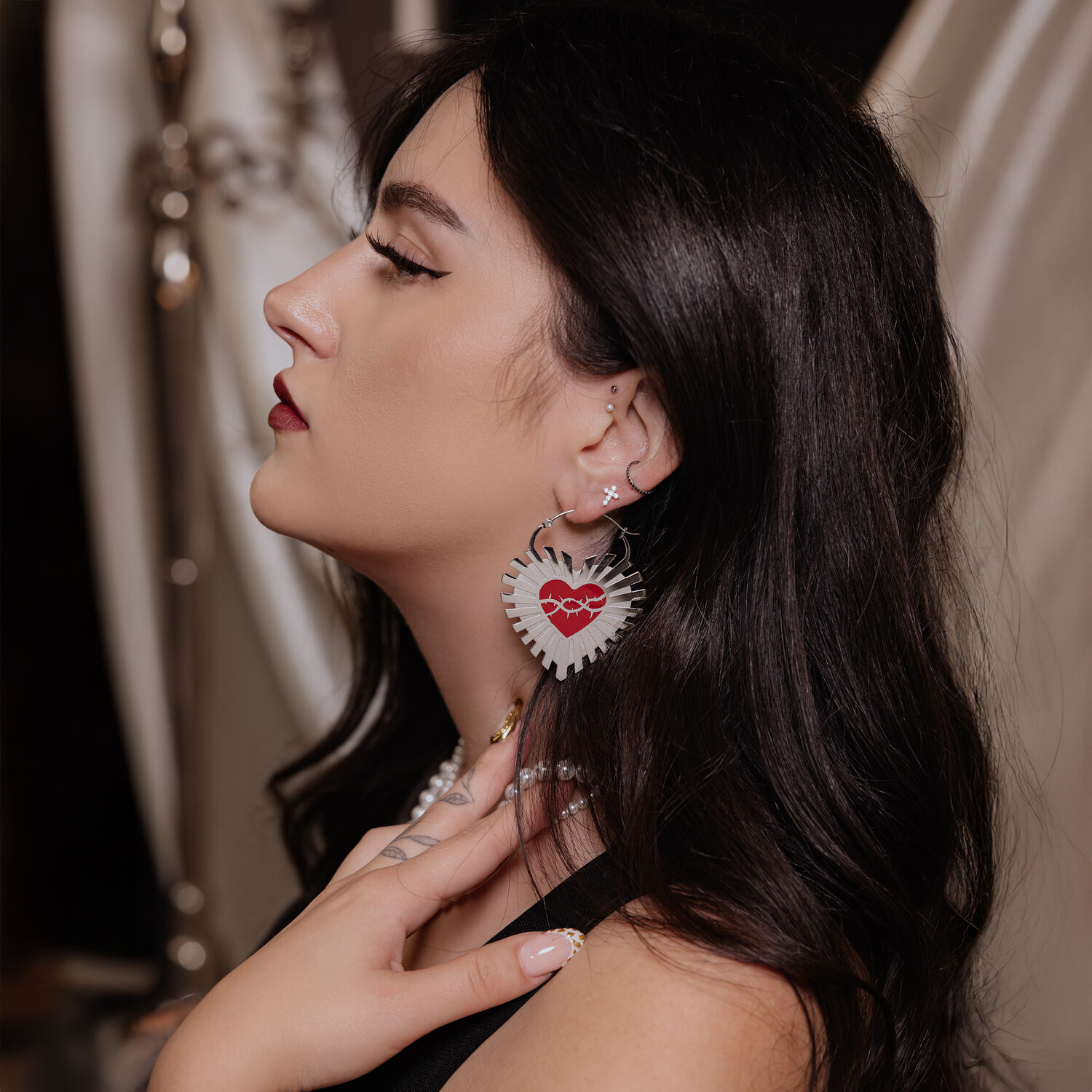 Donna con orecchini Barbed Wire Sacred Heart, capelli neri, sfondo elegante