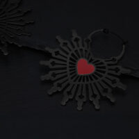 Orecchini neri in acciaio chirurgico con motivo a cuore rosso su sfondo scuro