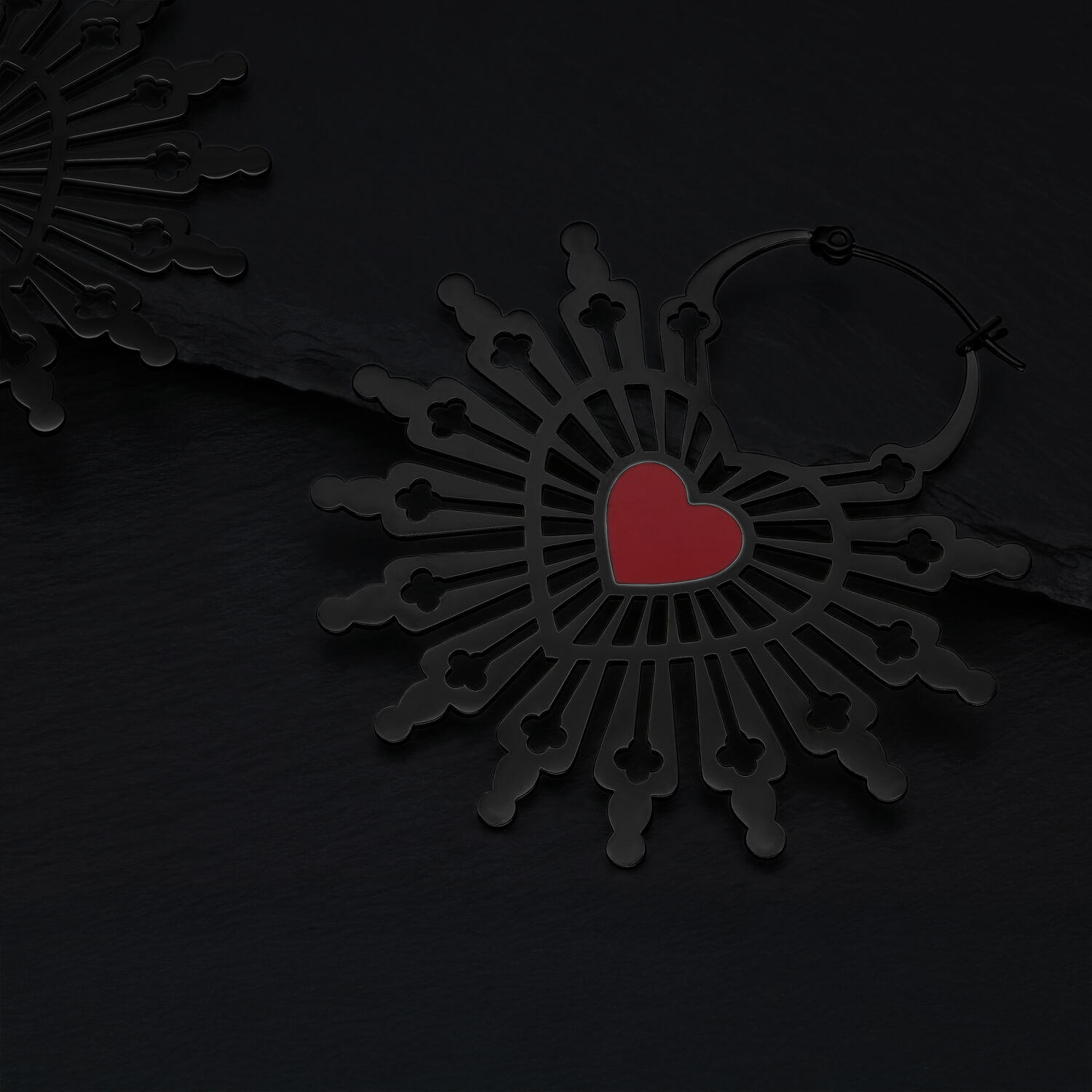 Orecchini neri in acciaio chirurgico con motivo a cuore rosso su sfondo scuro