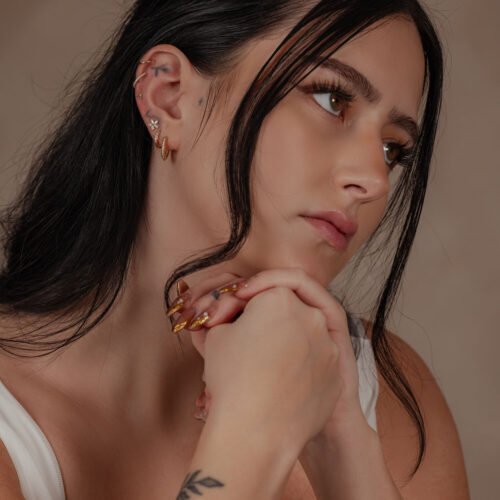 Donna con Fiore Moissanite in Oro 14K all'orecchio, sfondo discreto