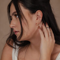 Primo piano di un orecchio con fiore in oro 14K e cristalli chiari, vista laterale