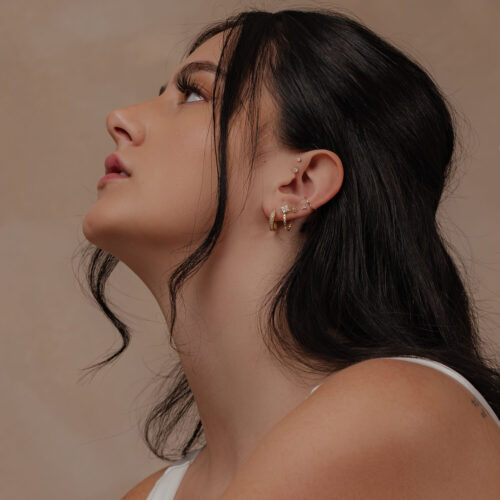 Donna con attacco 14K oro fiocco di neve nell'orecchio su sfondo neutro