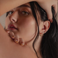 Primo piano di una donna con un attacco in moissanite d'oro 14K nell'orecchio, sfondo sfocato