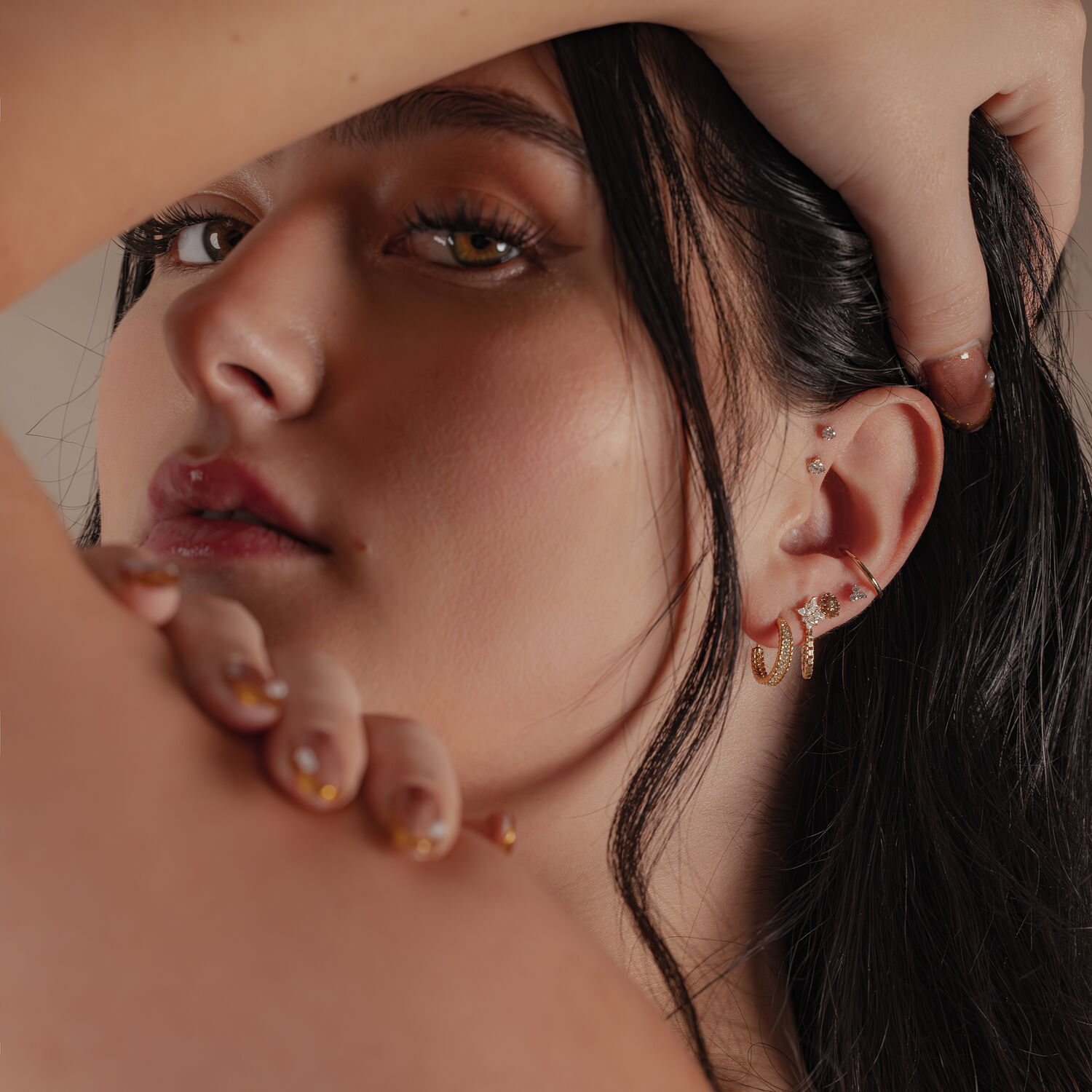 Primo piano di una donna con un attacco in moissanite d'oro 14K nell'orecchio, sfondo sfocato