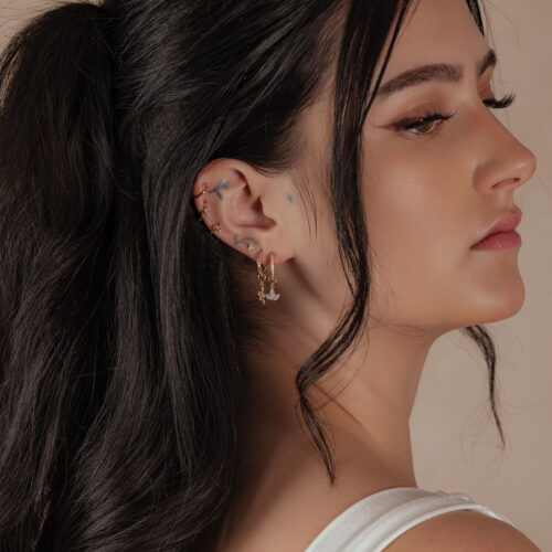 Donna con anello incernierato in oro 18K all'orecchio, profilo laterale, capelli scuri