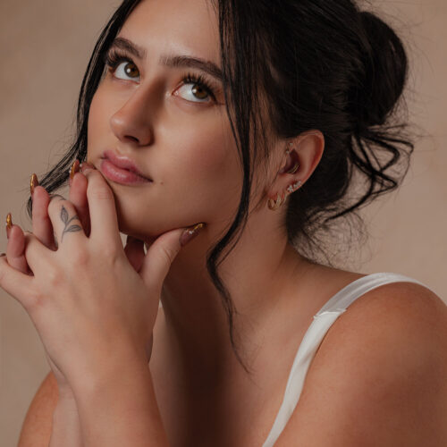 Primo piano di una persona con 14K Gold Cristallo per l'Orecchio su sfondo neutro