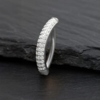 Clicker per ombelico in argento con cristalli scintillanti su sfondo scuro