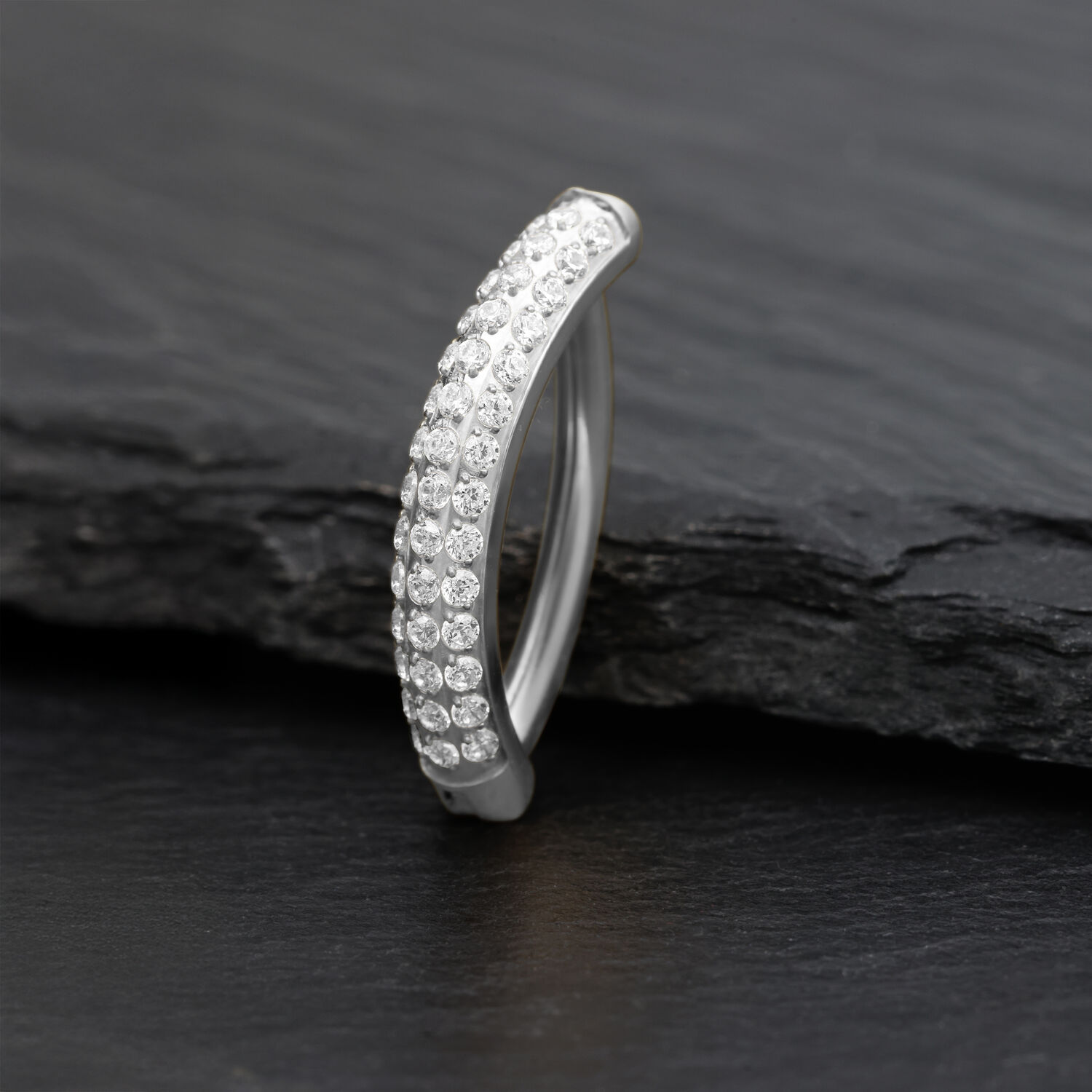 Clicker per ombelico in argento con cristalli scintillanti su sfondo scuro