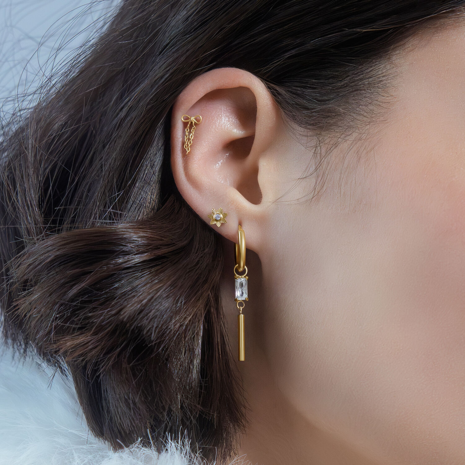 Pendente Push Fit dorato per piercing all'orecchio Pendente Push Fit dorato sull'orecchio di una donna con capelli corti castani, primo piano