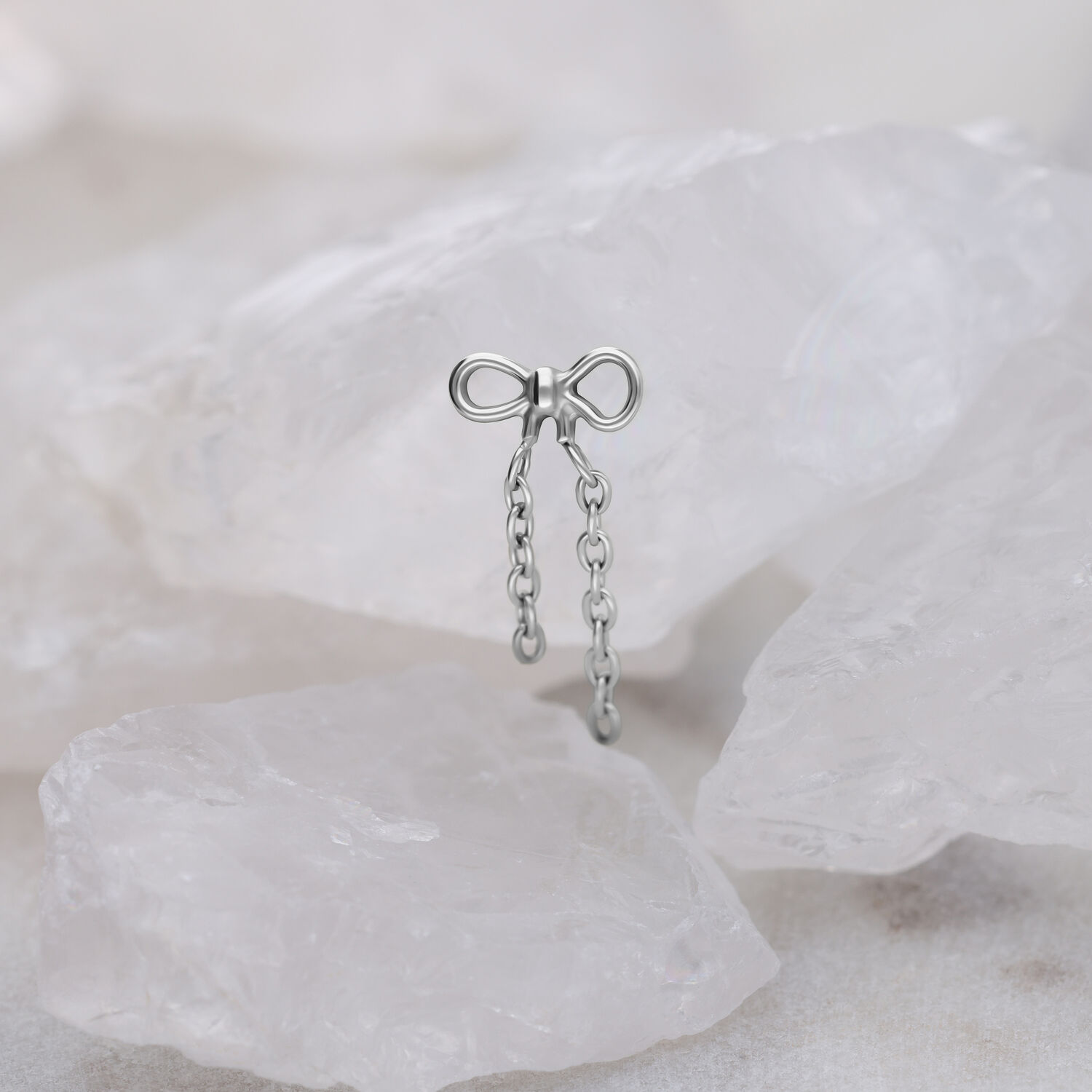 Attacco Push Fit argentato a forma di fiocco con catene su sfondo chiaro