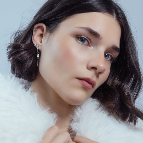 Donna con elegante punta per piercing Push Fit in argento sul padiglione auricolare, sfondo bianco