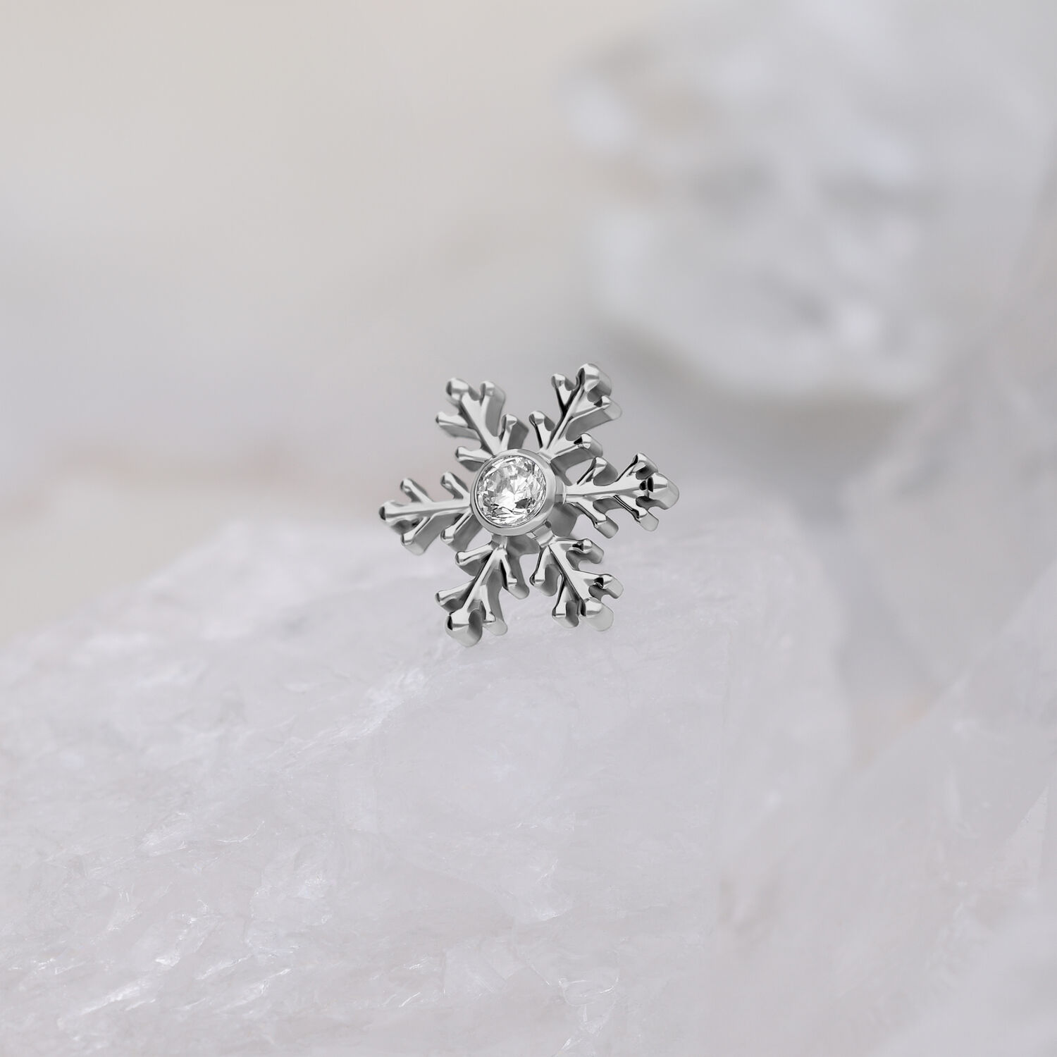 Punta piercing a fiocco di neve argentata con cristallo trasparente su sfondo bianco