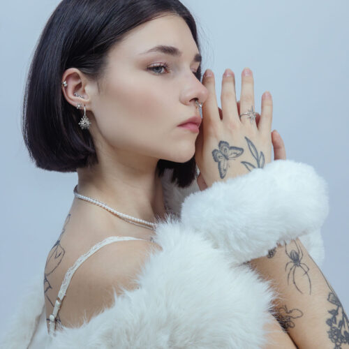 Donna con inserto Push Fit argento nell'orecchio, sfondo bianco