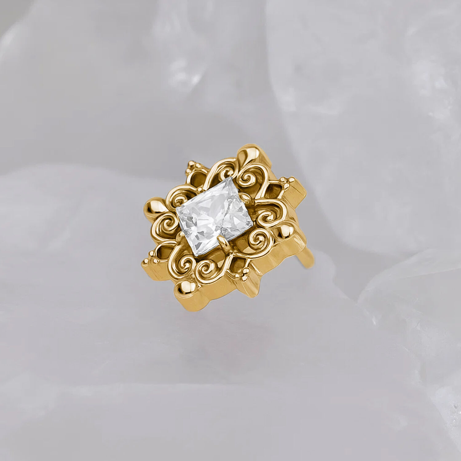 Accessorio in metallo dorato con cristallo chiaro su sfondo grigio