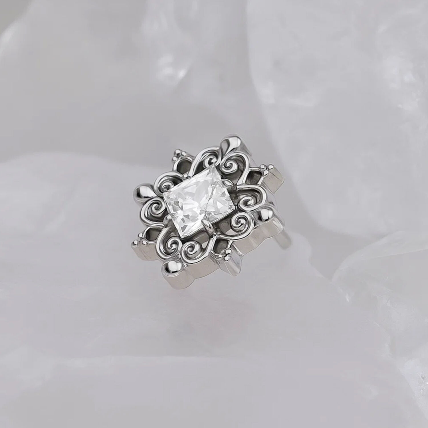 Accessorio in titanio argento con pietra cristallina su sfondo bianco