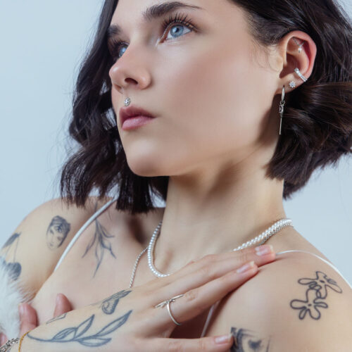 Donna con diversi piercing, cristallo nell'orecchio, look elegante