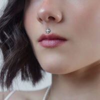 Primo piano di un cristallo per piercing in argento su un piercing Medusa di una donna su sfondo neutro