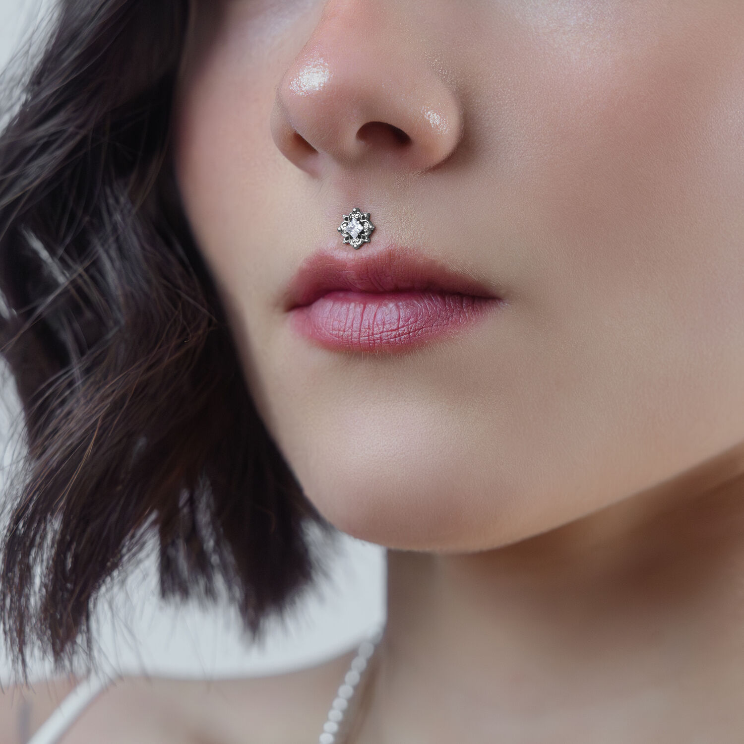 Primo piano di un cristallo per piercing in argento su un piercing Medusa di una donna su sfondo neutro