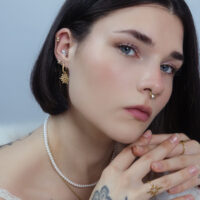 Donna con inserti piercing dorati all'orecchio e al naso
