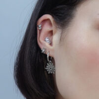 Donna con piercing Snow Angel in argento all'orecchio, sfondo neutro