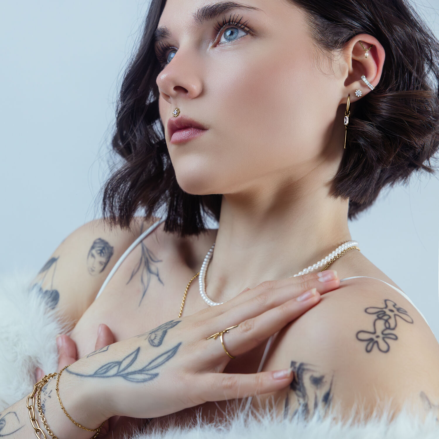 Donna con piercing Push Fit Ice Flower dorato nell'orecchio, sfondo bianco