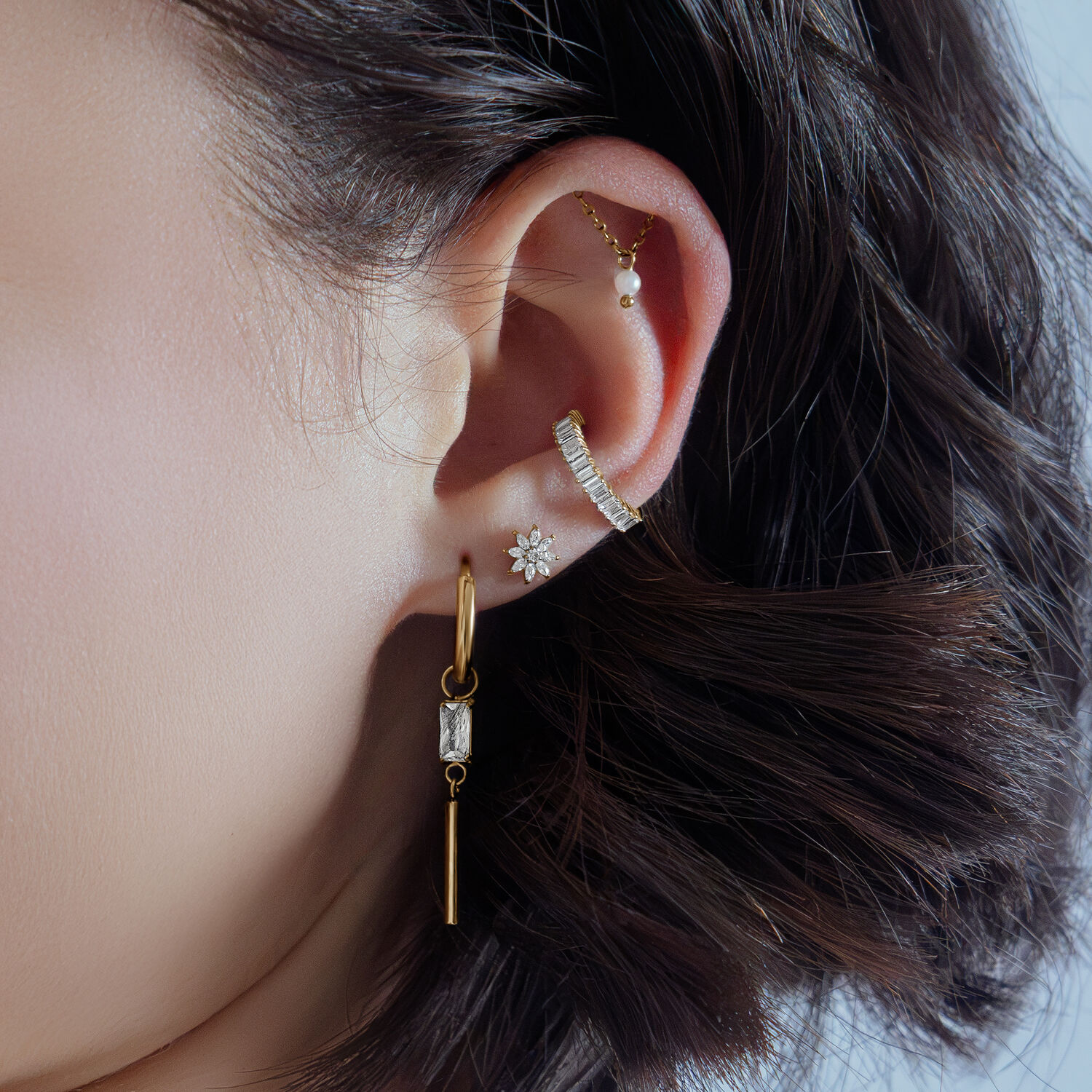 Orecchio con cristallo Ice Flower dorato, indossato con altri piercing dorati
