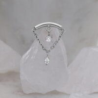 Ornamento elica argento con due cristalli chiari su sfondo marmorizzato