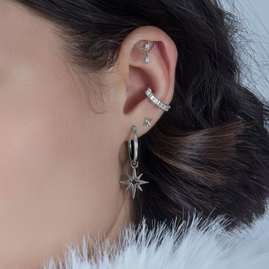 Accessorio elica in argento con cristalli su un orecchio, sfondo scuro