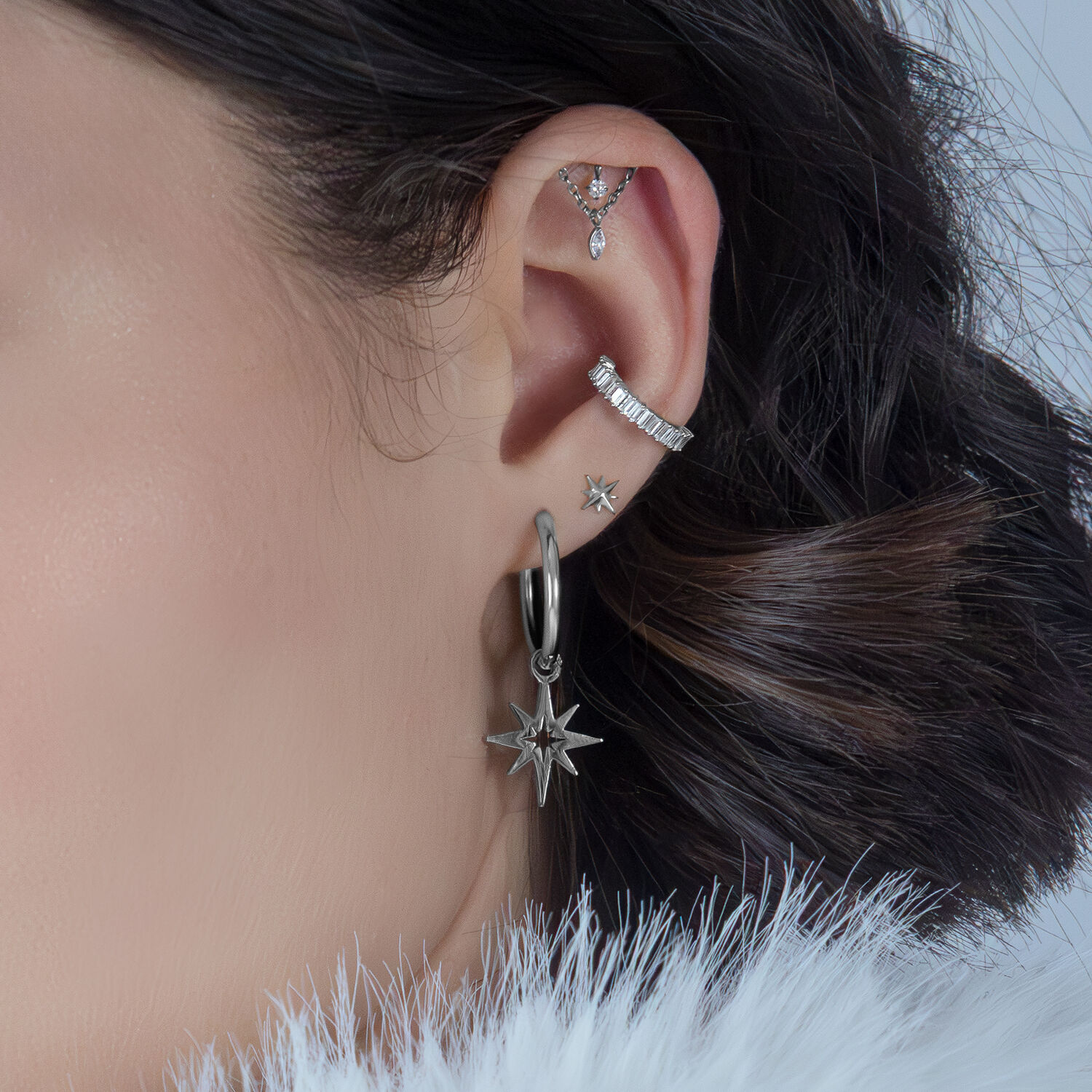 Accessorio elica in argento con cristalli su un orecchio, sfondo scuro