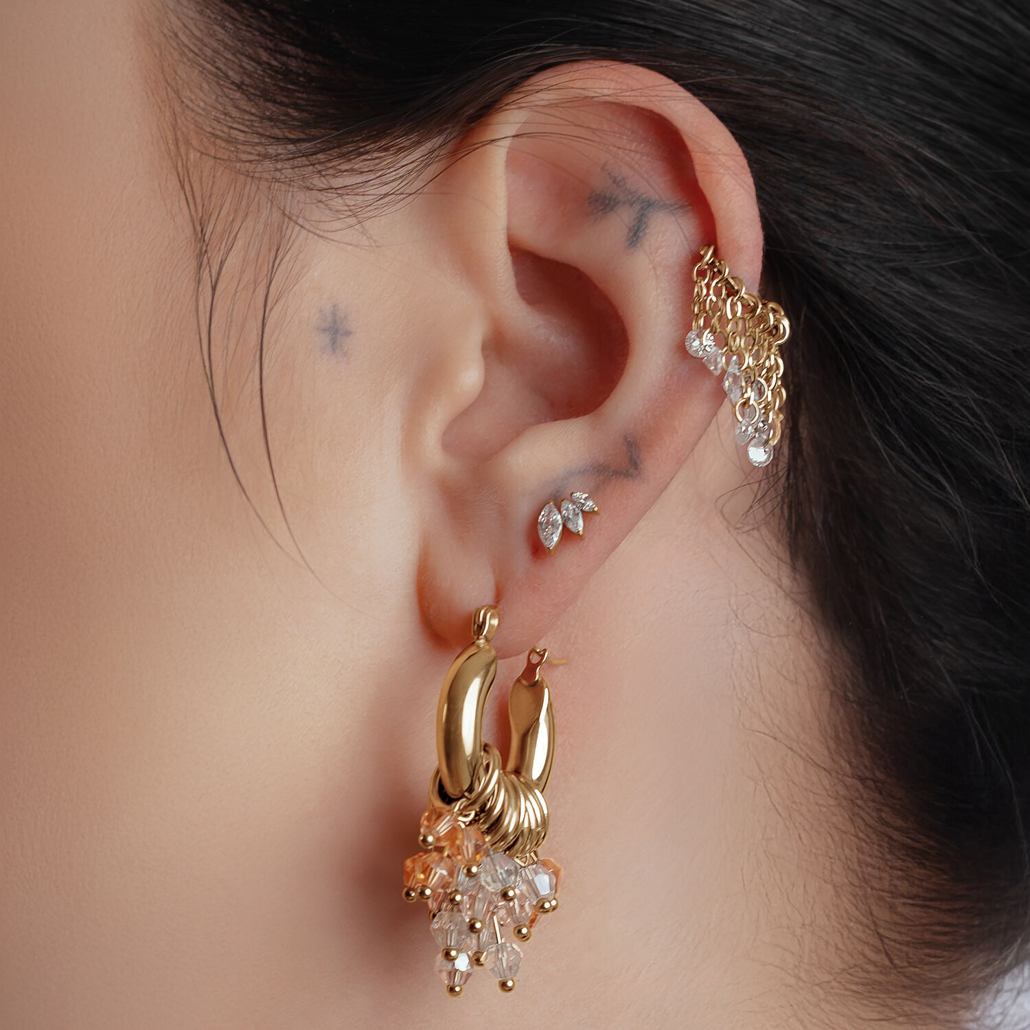 Orecchini Glamour Hoops dorati sull'orecchio di una persona con altri piercing
