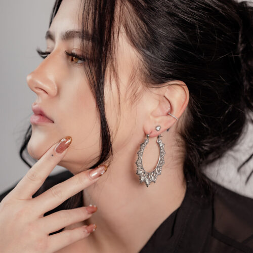 Donna con capelli neri indossa orecchini Sunflower Hoops in argento