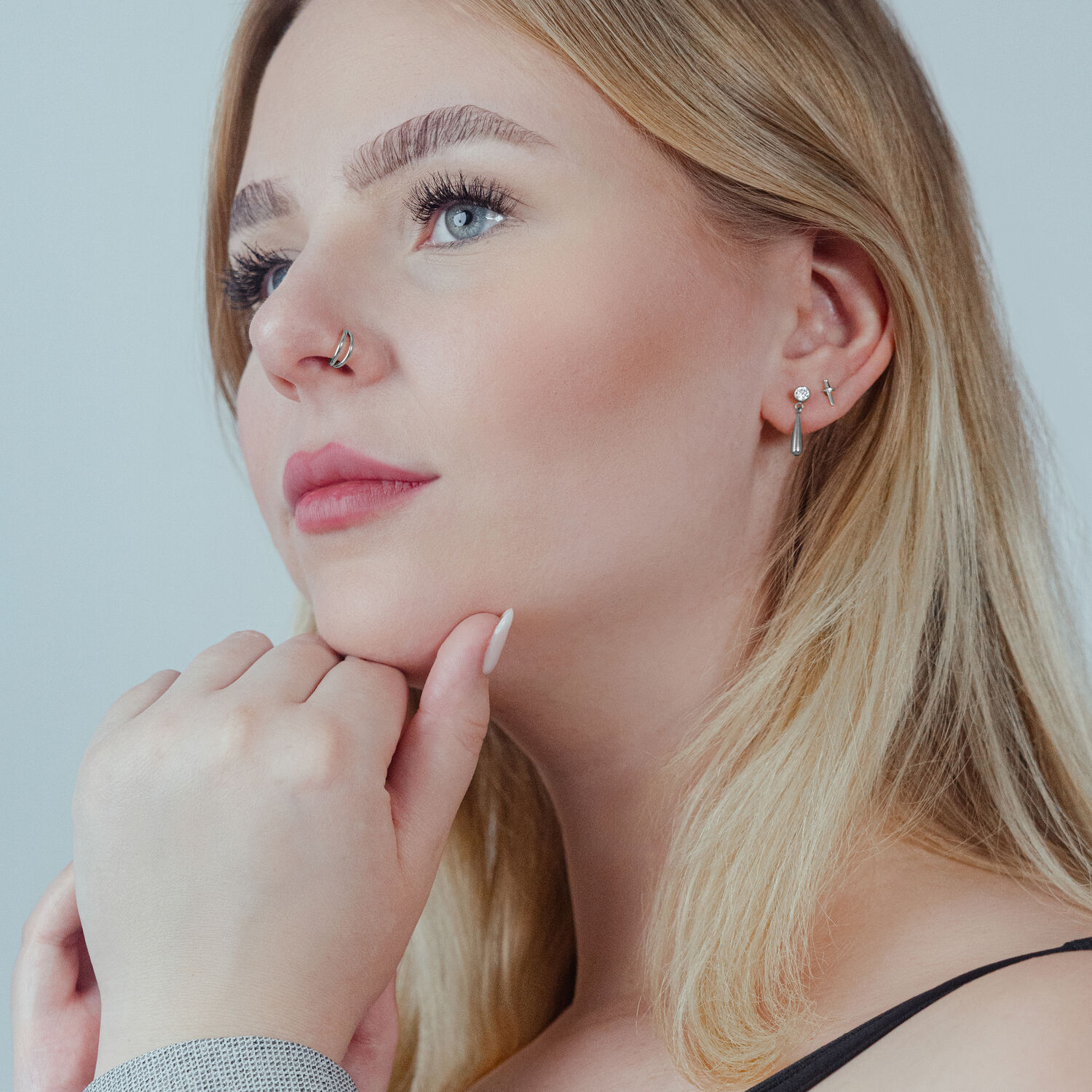 Donna con clicker a doppia fila in argento nell'orecchio e anello al naso, sfondo neutro