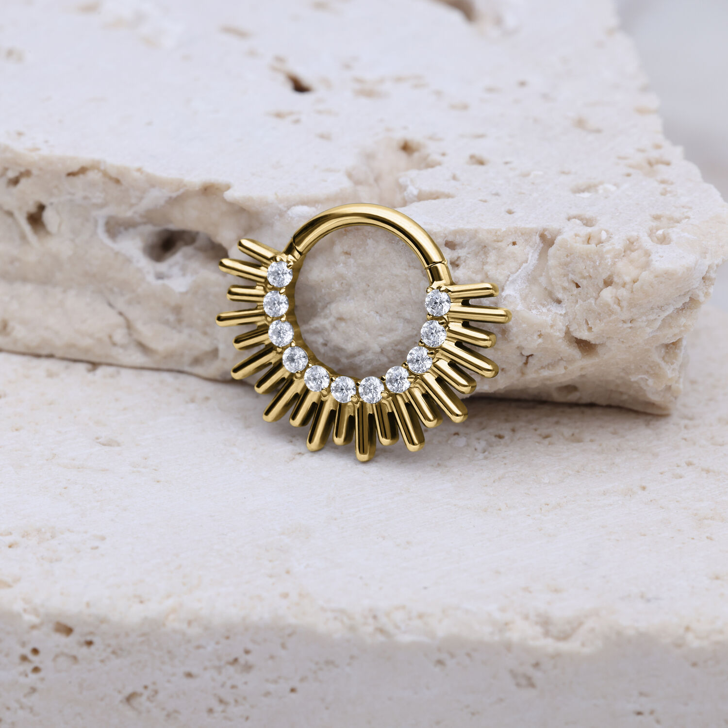 Septum Clicker dorato con design a raggi e cristalli su pietra chiara