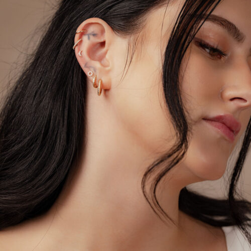 Donna con 14K Gold Moissanite Moon Attachment nell'orecchio su sfondo neutro