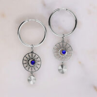 Orecchini a cerchio in argento con cristallo blu scuro su sfondo grigio chiaro