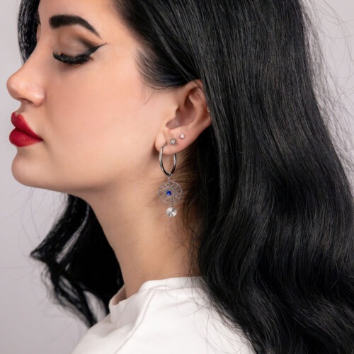 Donna indossa cerchi in argento e oro con cristalli blu scuro