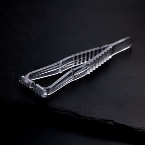 Pinza trasparente per piercing al setto in plastica su sfondo scuro e liscio