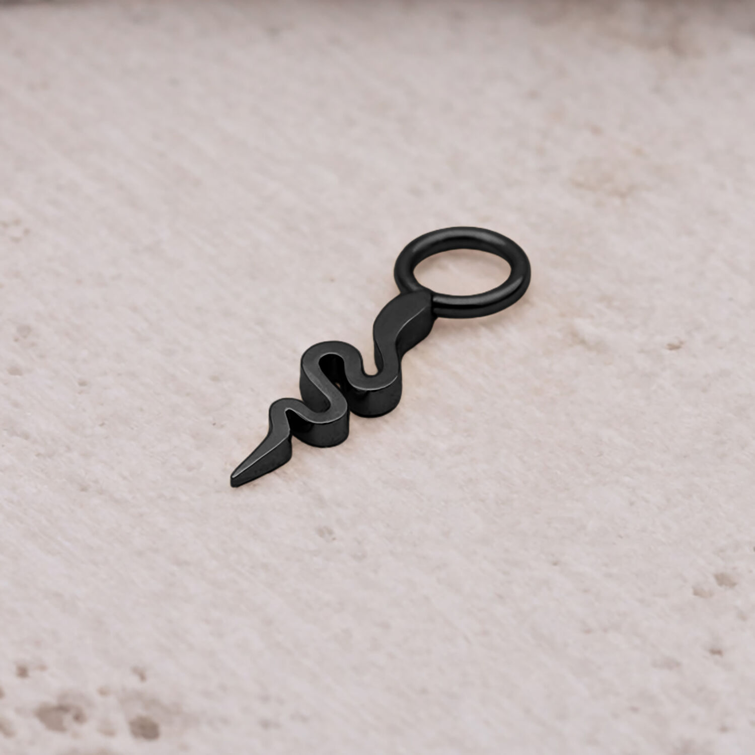 Ciondolo a forma di serpente nero in acciaio chirurgico su sfondo chiaro