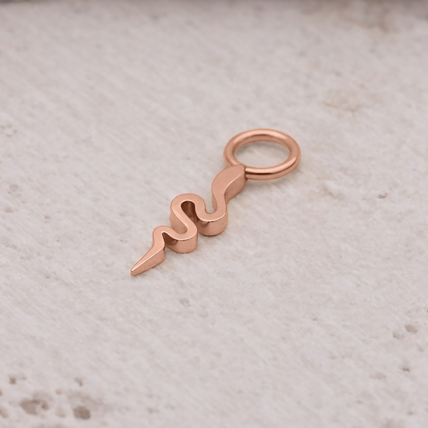 Ciondolo serpente in oro rosa in acciaio chirurgico su sfondo chiaro