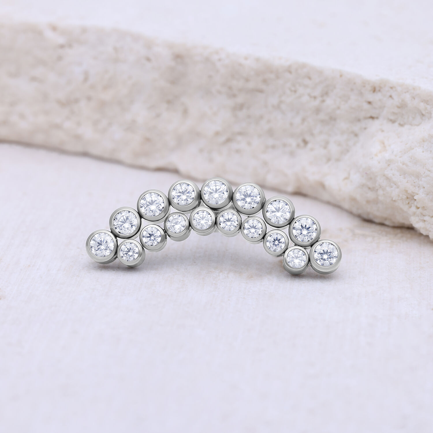 Accessorio in argento con pietre cristalline, a forma di semicerchio su sfondo chiaro