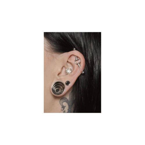 Primo piano di un orecchio con piercing industriale argento e altri gioielli per l'orecchio