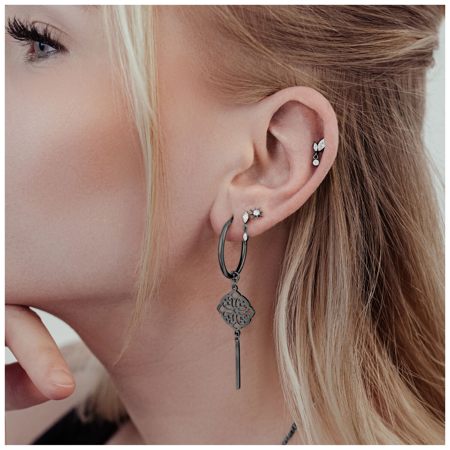 Orecchini neri Clover Hoops in acciaio chirurgico all'orecchio di una donna