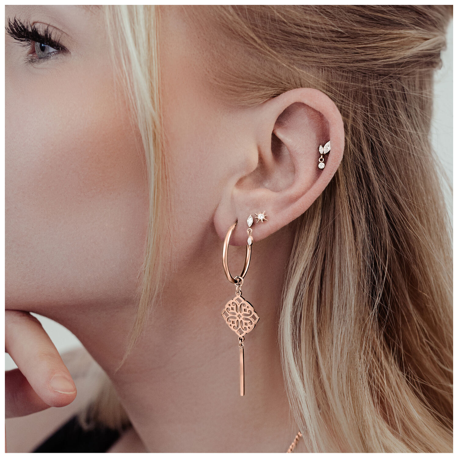 Donna con orecchini Clover Hoops in oro rosa in acciaio chirurgico, indossati all'orecchio sinistro